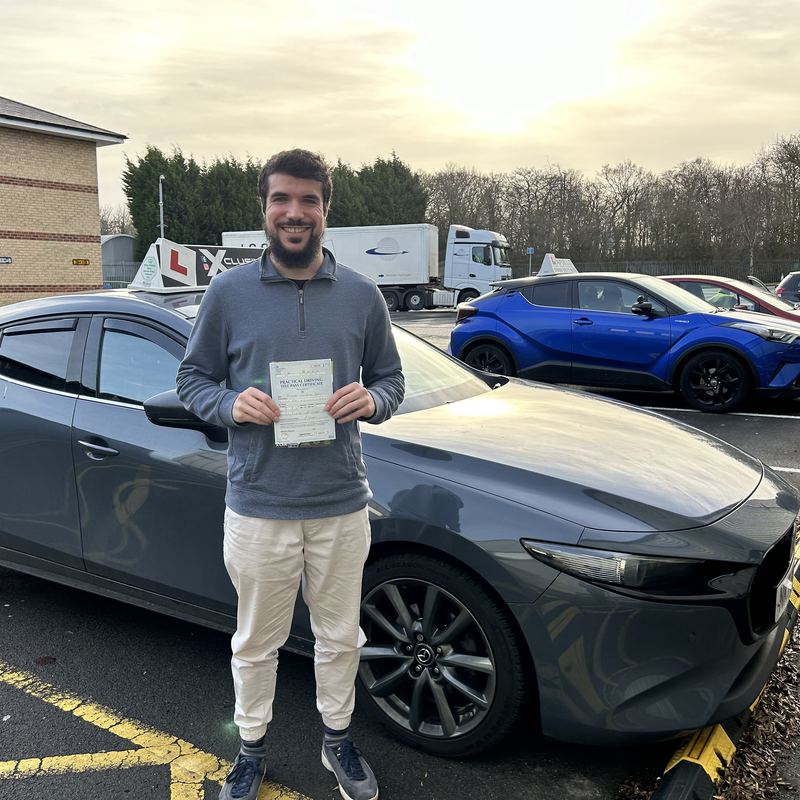 An Xclusive Driving student holding their DVSA practical test pass certificate by the car