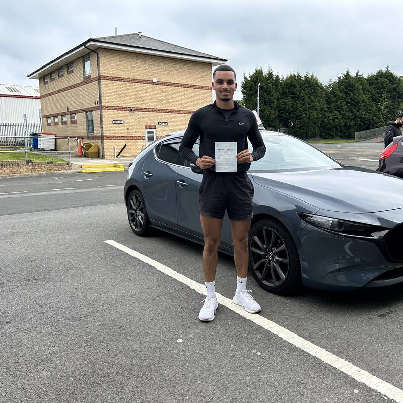 An Xclusive Driving pupil holding their practical test pass certificate at the driving test centre