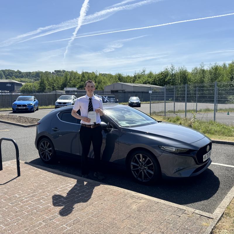 A learner driver holding their driving test pass certificate next to the Xclusive Driving car
