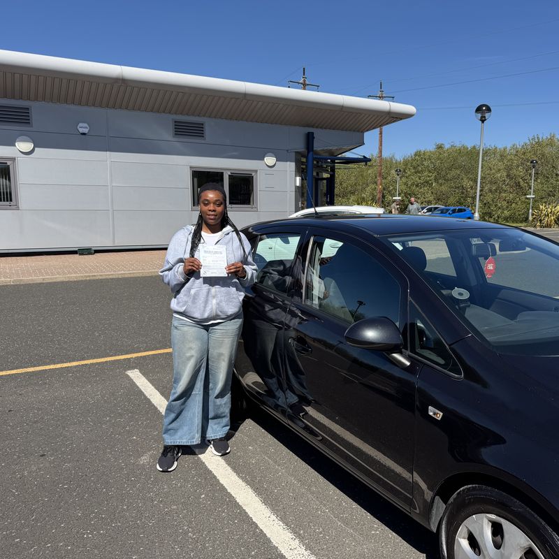 An Xclusive Driving student holding their DVSA practical test pass certificate in the test centre car park